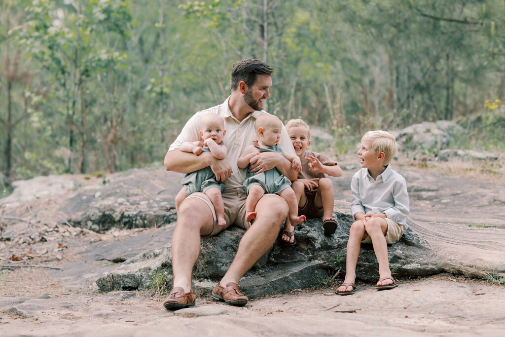 Close-up of family hands intertwined on mossy rock surface