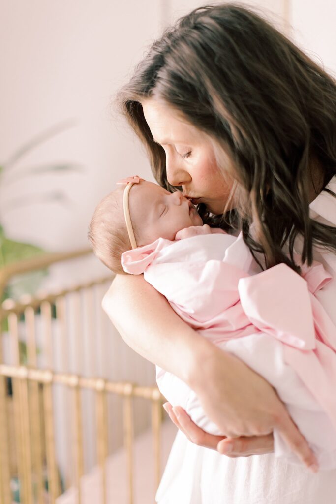 baby girl swaddled in pink blanket with headband in home setting