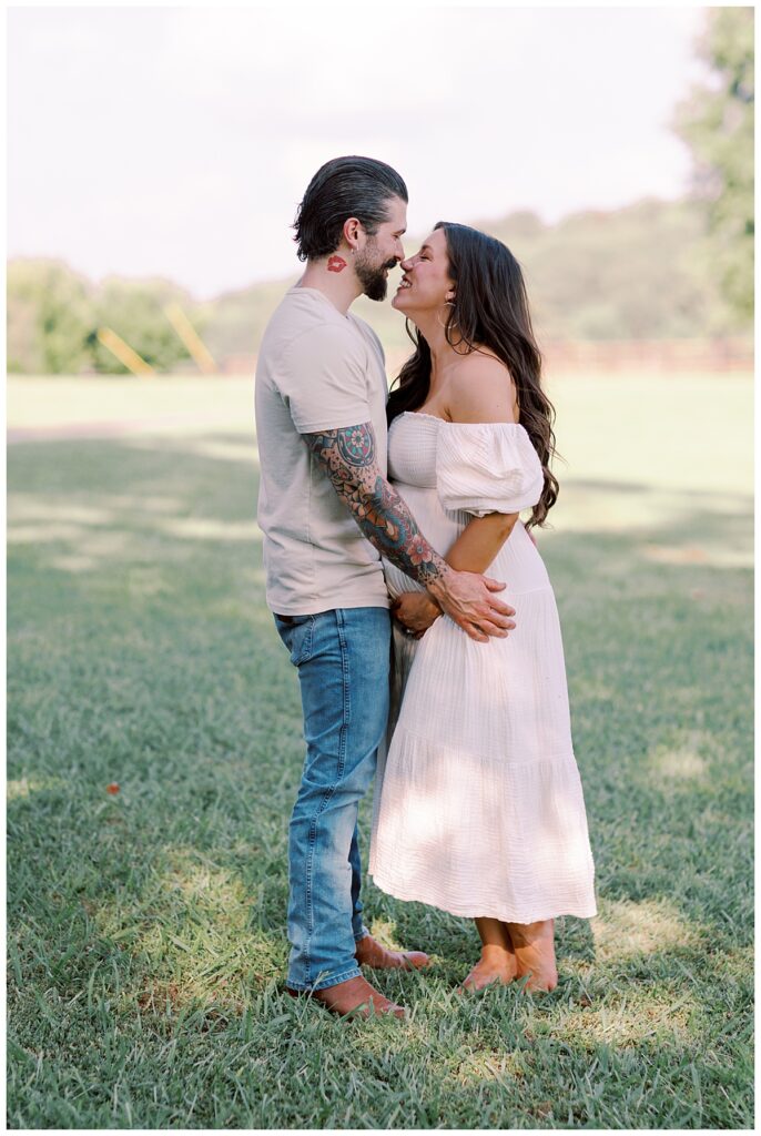 Elizabeth and Dayne facing each other with hands on belly, golden hour light
