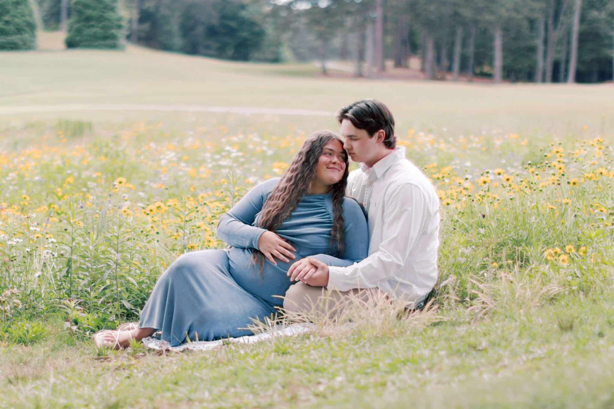 Adara and Grayson sitting together in a wildflower field during their Fairfield Plantation maternity session in Villa Rica, Georgia.