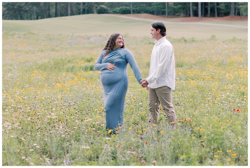 Expecting mother in a blue dress standing among summer wildflowers at Fairfield Plantation in Villa Rica, GA.
