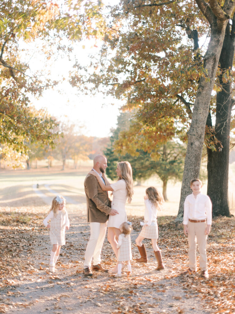 Parents and their young children interacting beneath colorful autumn trees